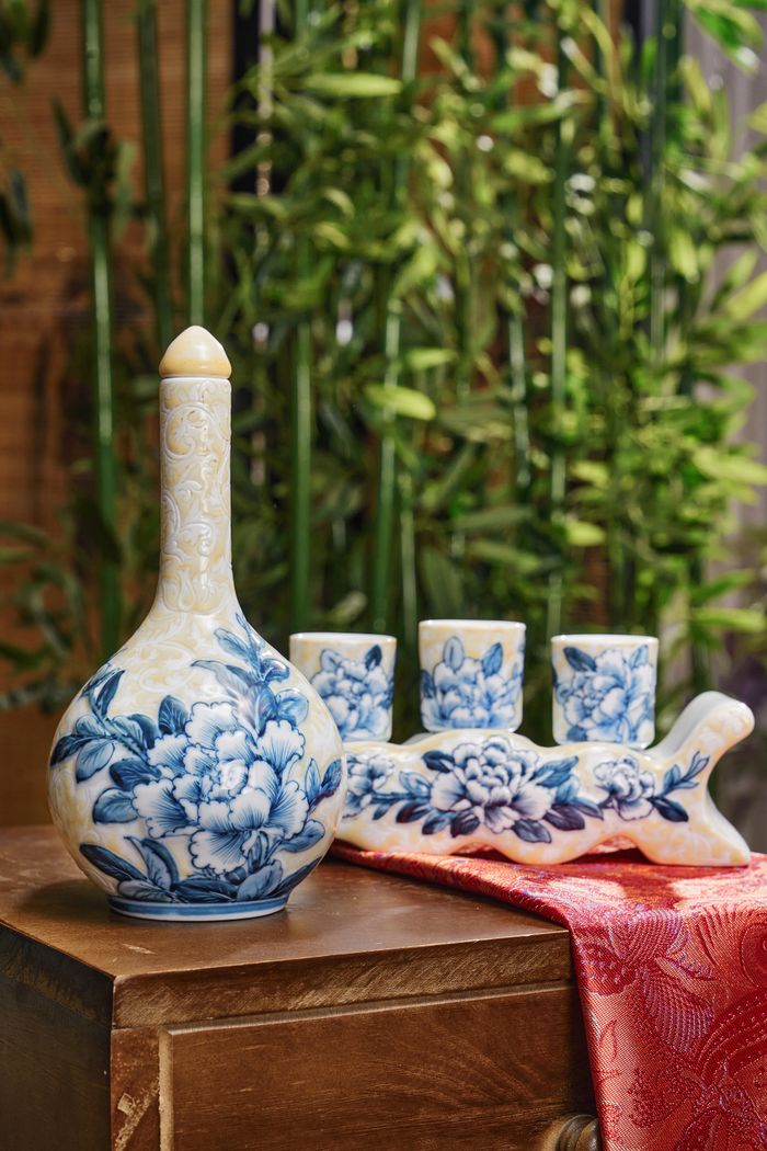 A beautifully ornate ceramic vase with a traditional floral design, set against a bamboo backdrop.