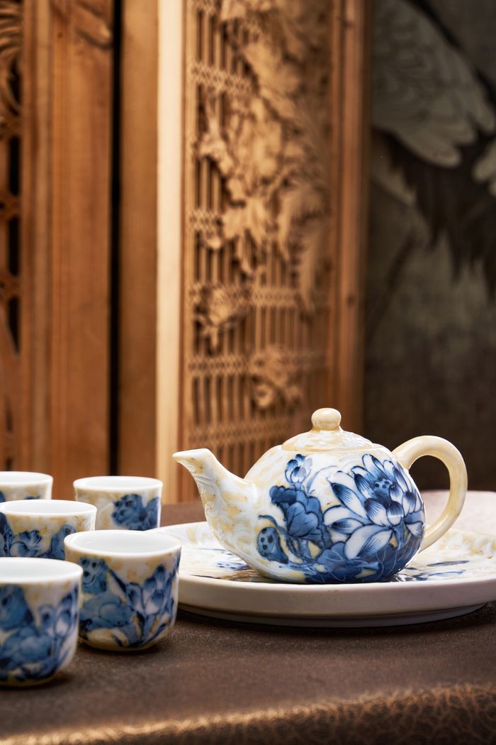 Beautiful blue and white porcelain teapot with cups set on a tray, featuring floral designs.